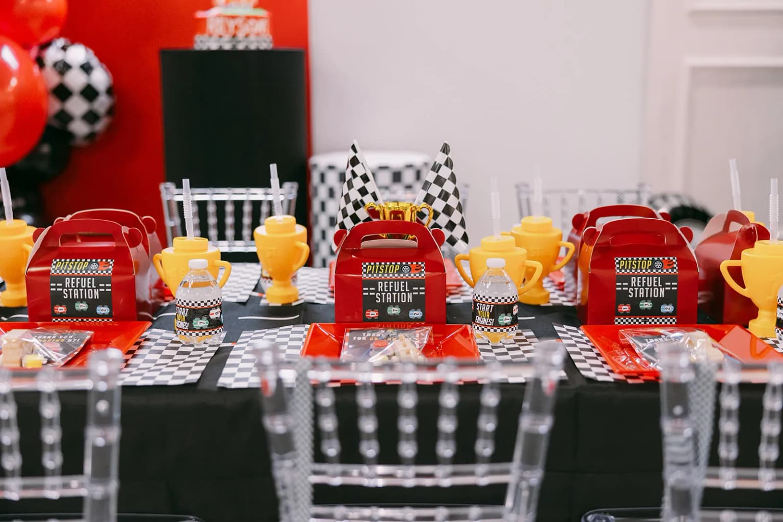 Racecar themed kids birthday table setup with checkered flags and party favors at Aramas Events