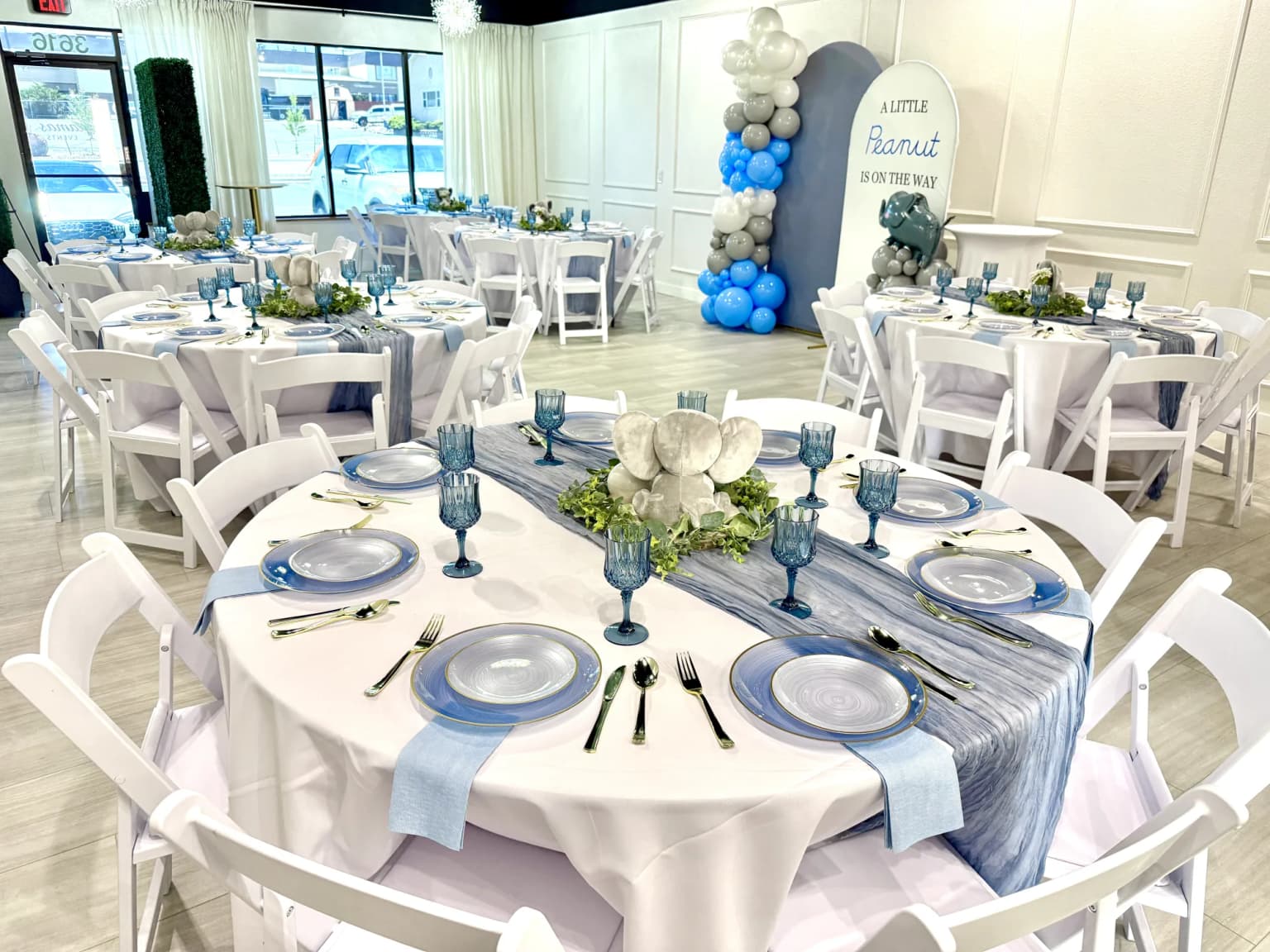 Little peanut themed baby shower room setup with blue table settings and balloon backdrop at Aramas Events