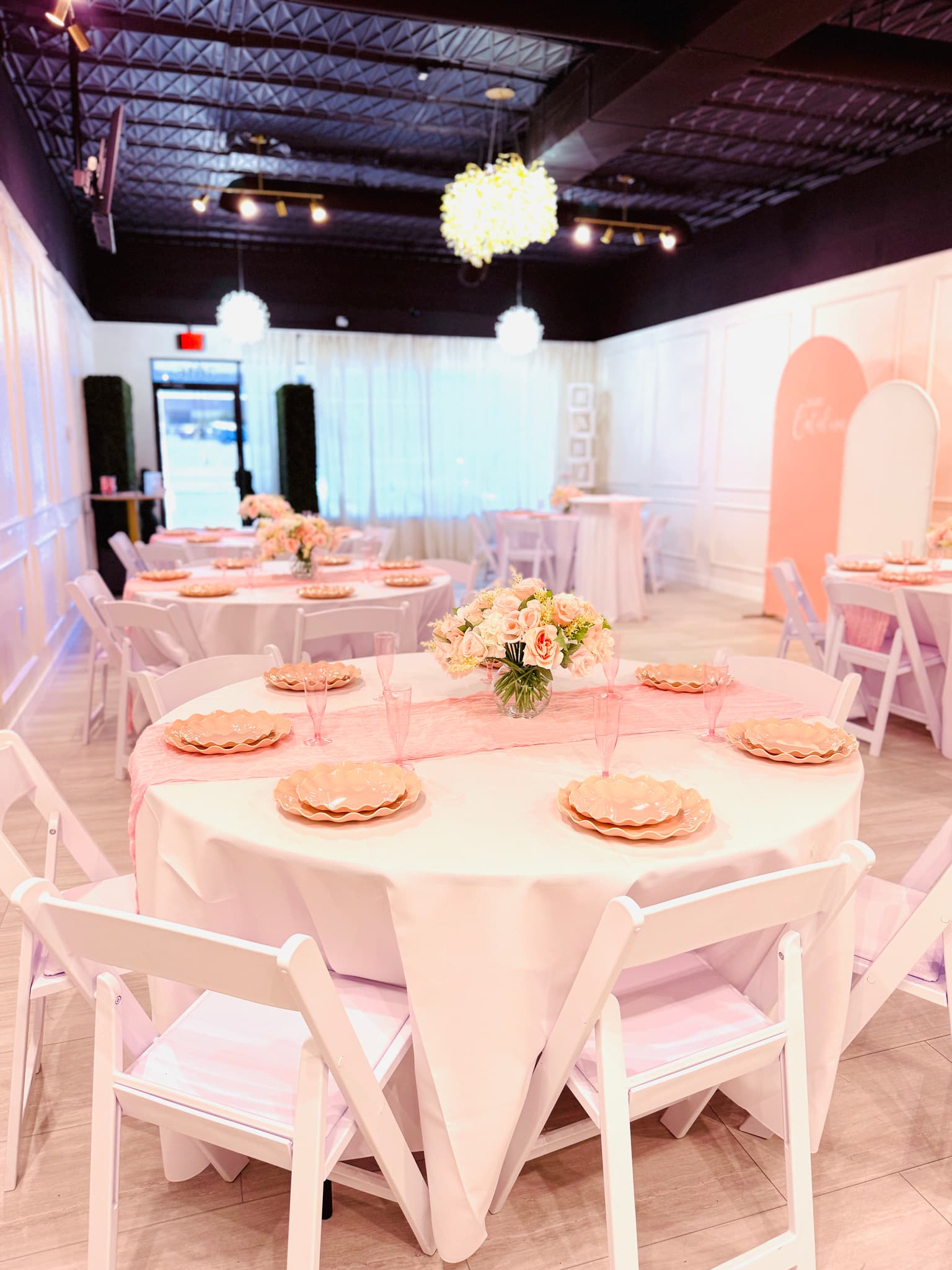 Pink baby shower table setup with round tables and floral centerpieces at Aramas Events