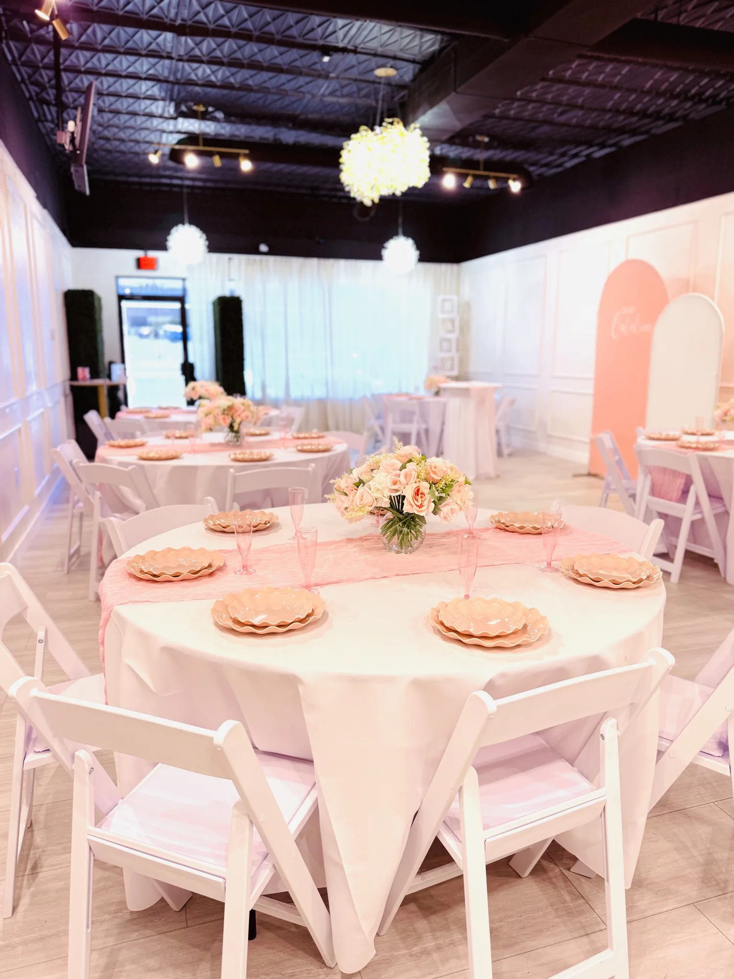 Pink baby shower table setup with round tables and floral centerpieces at Aramas Events