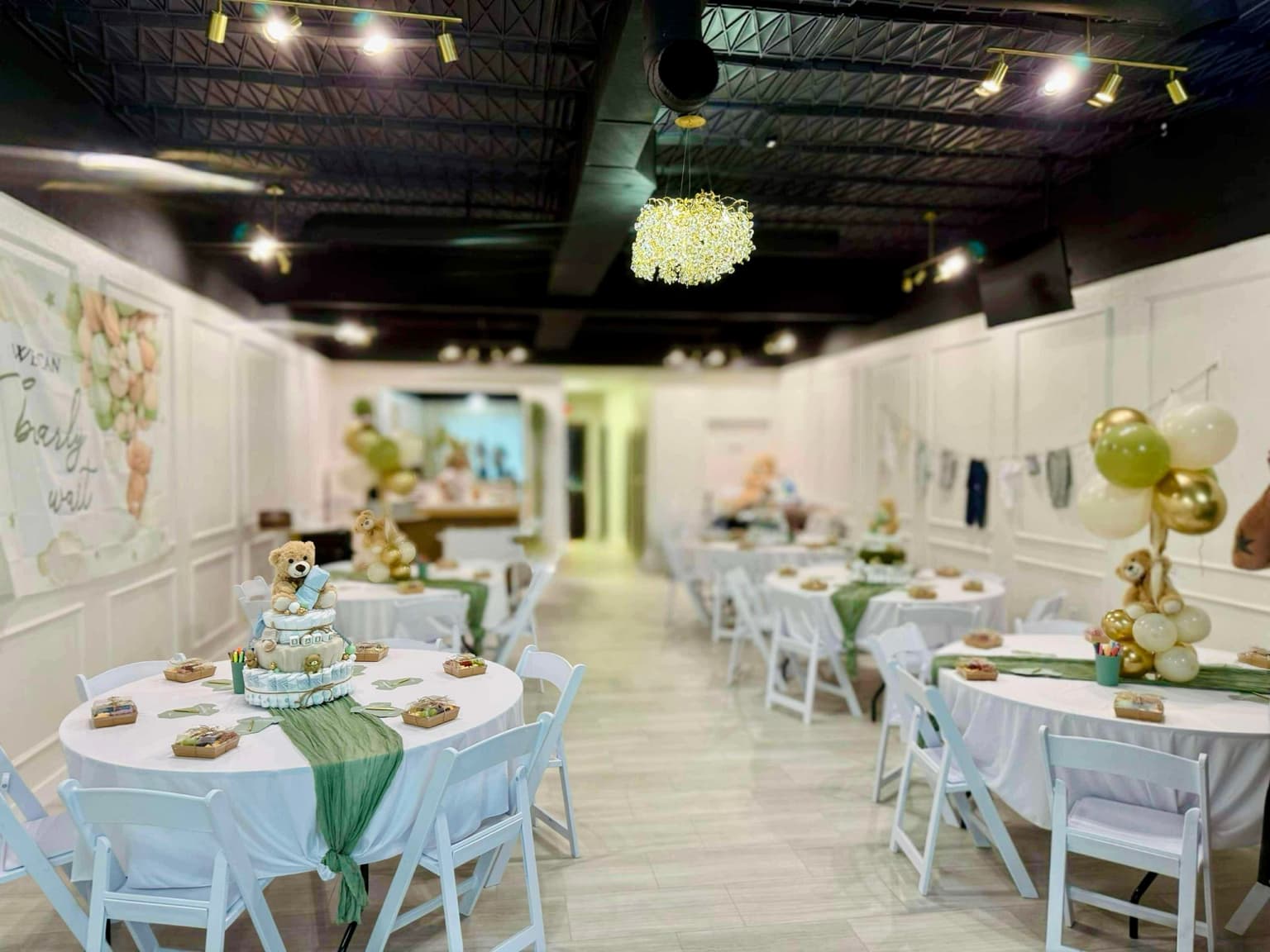 Baby shower room layout with round tables and green accent decor at Aramas Events