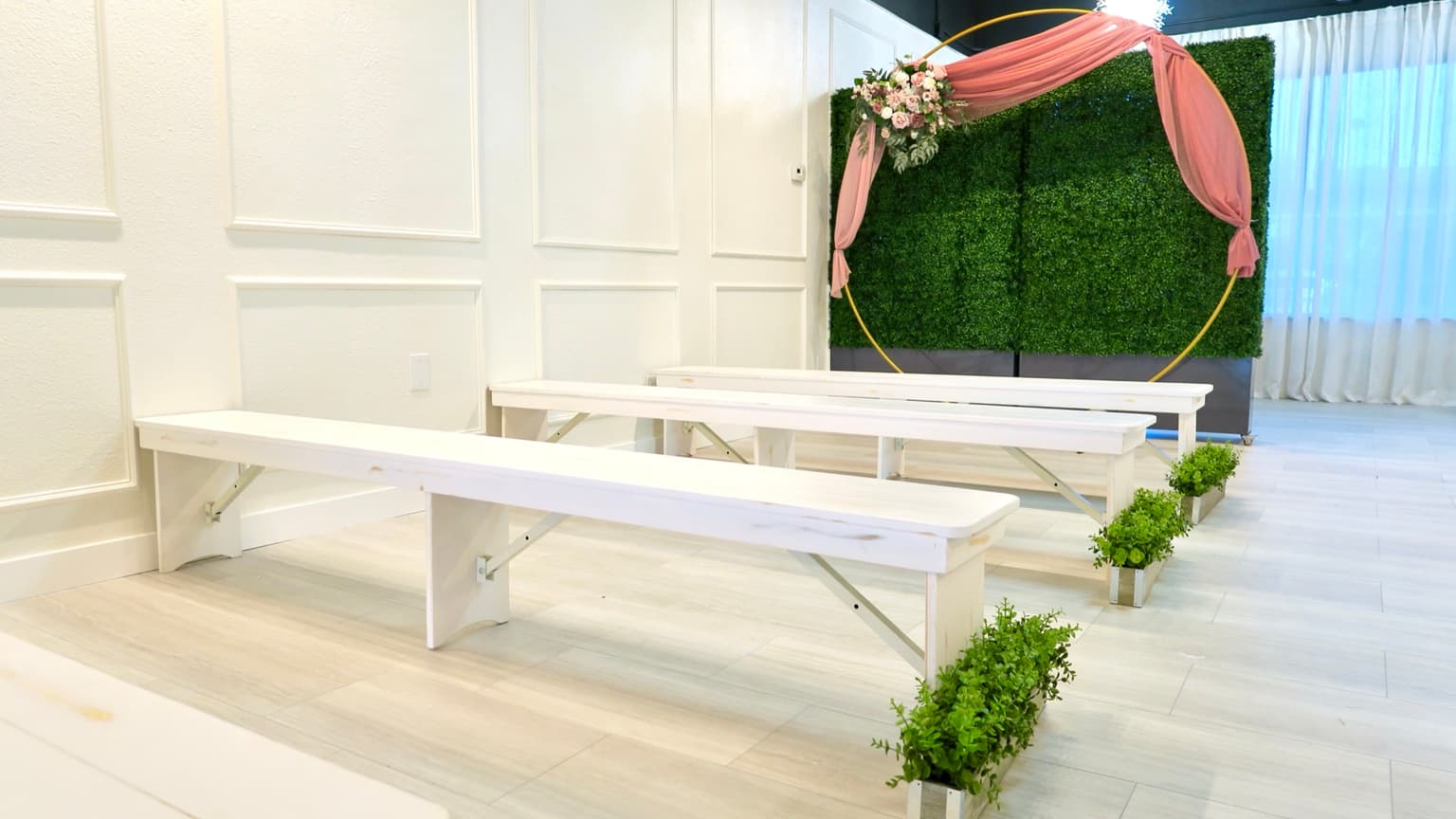 Ceremony setup with white benches and floral arch at Aramas Events