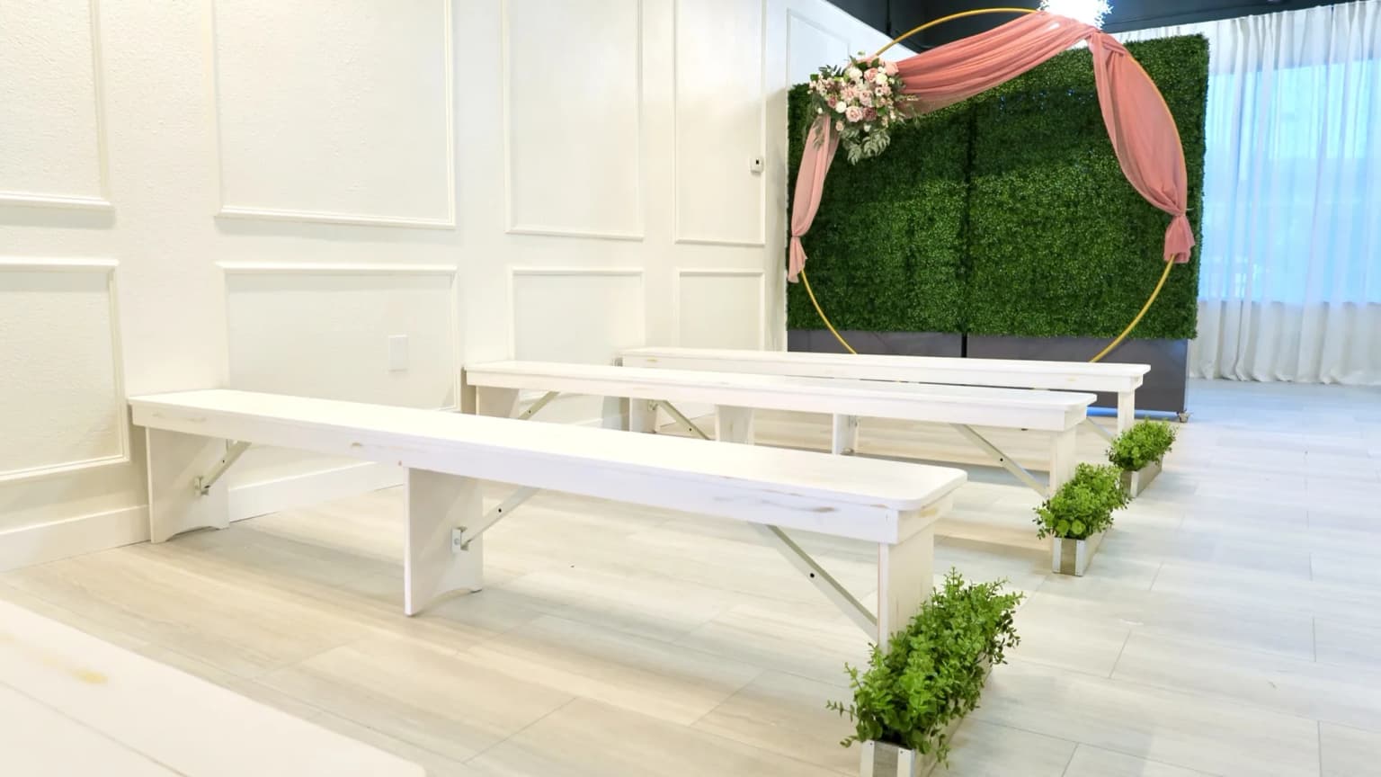 Ceremony setup with white benches and floral arch at Aramas Events